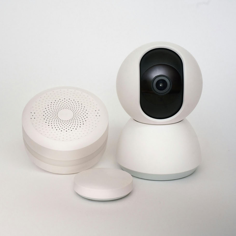 Modern minimalist smart home devices including security camera and sensors in white.